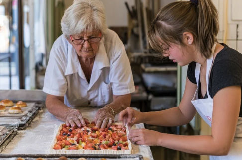 Small bakery team carefully preparing a fruit tart together in a working kitchen