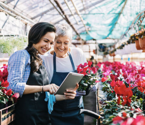 Small business team in a greenhouse reviewing a tablet together—digital tools for customer follow-up